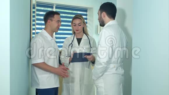两名男医生正在讨论女护士正在做笔记视频的预览图