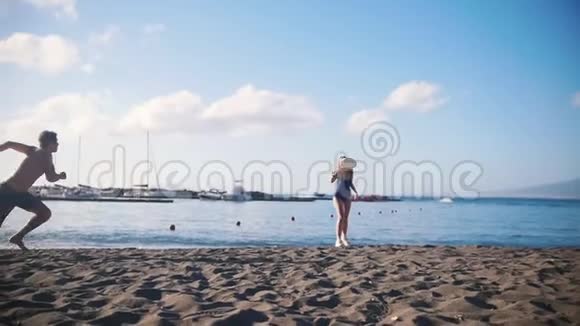 一个年轻人和他的女朋友在海滩上玩飞盘落在沙滩上视频的预览图