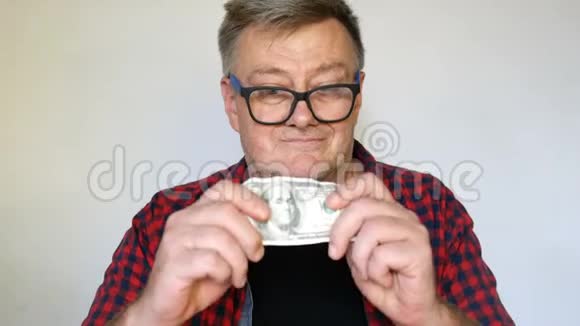 古怪的白发老人手里拿着一张一百美元的钞票对此非常高兴视频的预览图