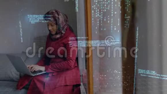 在她的房间里一个戴着头巾的女人在笔记本电脑上快速地用二进制代码视频的预览图