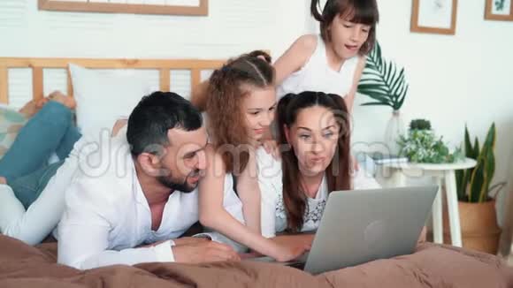 爸爸妈妈和两个女儿在笔记本电脑上玩电脑游戏慢动作视频的预览图