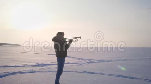 多莉放大了白种人音乐家的镜头在侧面完成吹喇叭的冬季自然背景视频的预览图