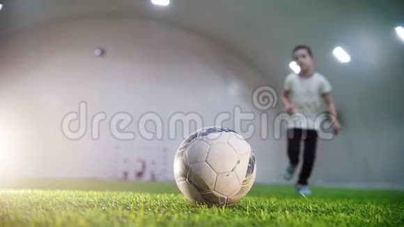室内足球场一个小男孩跑到球前拿着球跑开视频的预览图