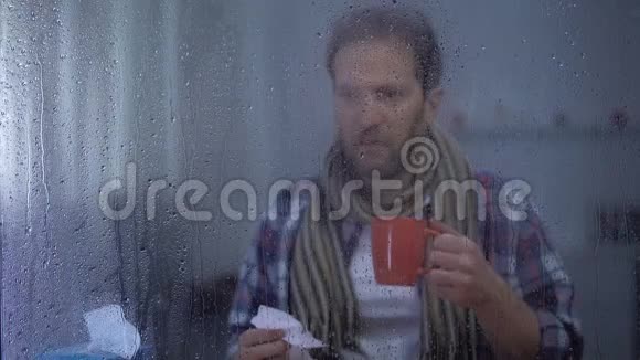 雨天戴围巾打喷嚏在家喝热茶的病人流感病毒视频的预览图