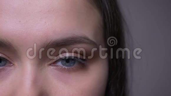 年轻迷人的女性脸上的特写镜头蓝色闪闪发光的眼睛用微笑的表情看着相机视频的预览图