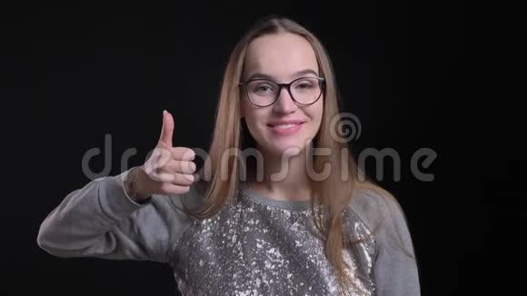 戴眼镜的年轻有魅力的时髦女性的特写镜头看的时候竖起大拇指开心地笑视频的预览图