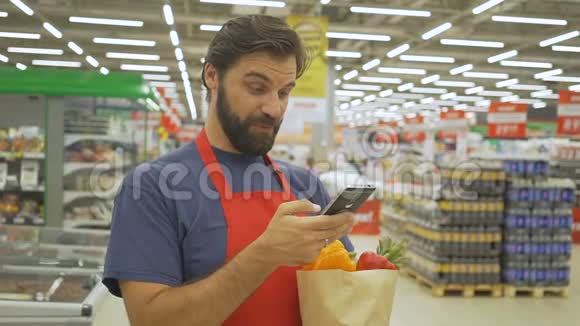 微笑超市员工使用手机拿着购物袋在超市视频的预览图