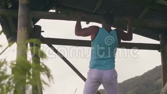 运动男子挂在木制横杆上训练腹肌户外男性腹肌在水平杆上锻炼反观运动员视频的预览图