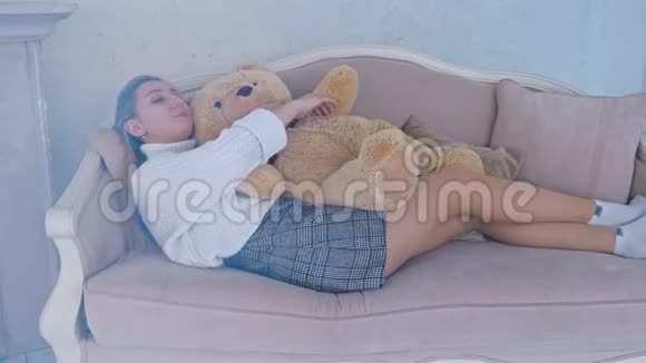 美丽的女孩睡在沙发上抱着泰迪熊视频的预览图