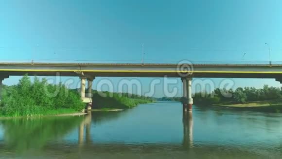 一辆汽车在宁静的河流上沿着桥路快速行驶的鸟瞰图4K视频的预览图