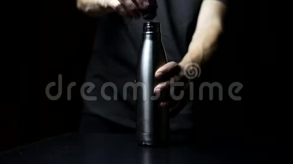 工作室形象特写男手放在盖子上可重复使用钢热水瓶在黑色背景上视频的预览图