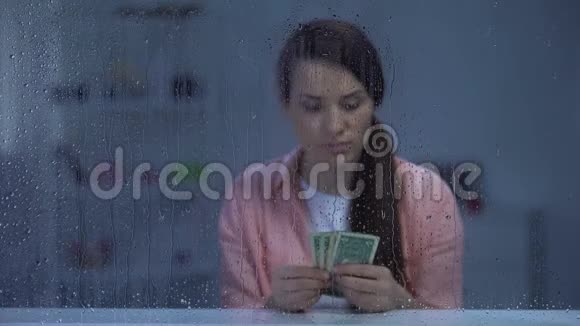 中年妇女在雨窗后数钱预算差贫穷视频的预览图