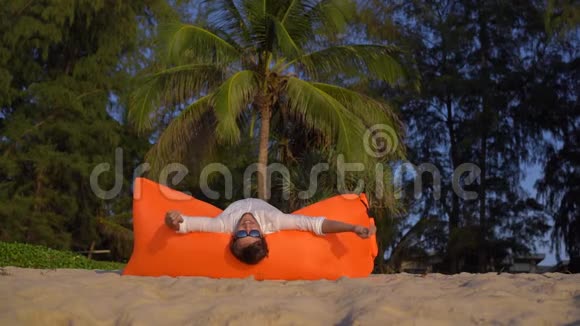 一个年轻人在美丽的海滩上的充气沙发上玩得很开心视频的预览图