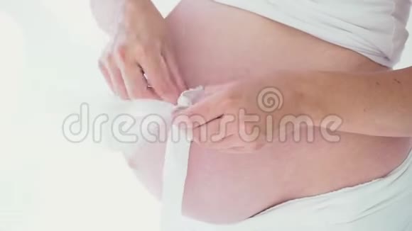 穿着内衣的怀孕妈妈在玩婴儿鞋带丝带的腰带视频的预览图
