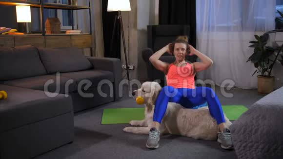 有宠物狗的运动女人做仰卧起坐运动视频的预览图