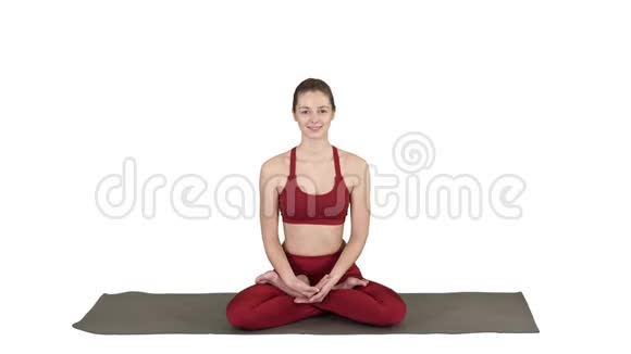 美丽的年轻女子坐在瑜伽姿势莲花改变位置她的手在白色的背景视频的预览图
