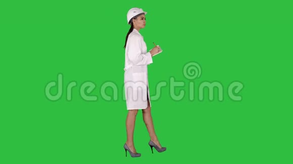 戴着头盔的女工程师拿着笔和清单在绿色屏幕上行走时放下一些东西Chroma视频的预览图
