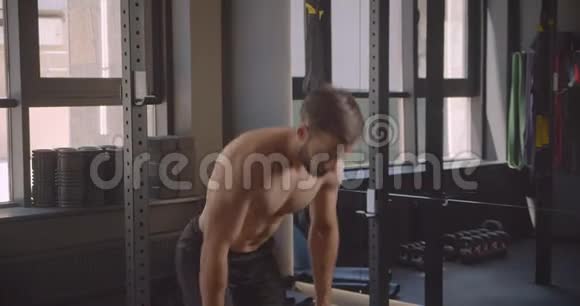 赤膊肌肉发达的白种人与哑铃一起在健身房锻炼的特写镜头视频的预览图