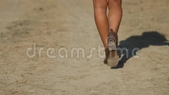 美丽的女性双腿踏在尘土飞扬的道路上视频的预览图