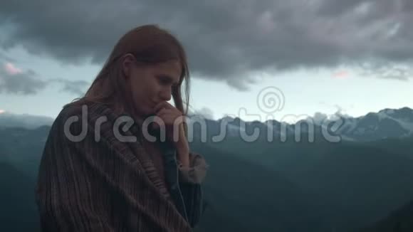 一个年轻的浪漫女孩的画像在山的背景上一个美丽的女孩在雪后看日落视频的预览图