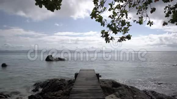 复古和古老的木桥在海滩和海洋的中午与海滩海洋阳光岩石风和波浪周围视频的预览图