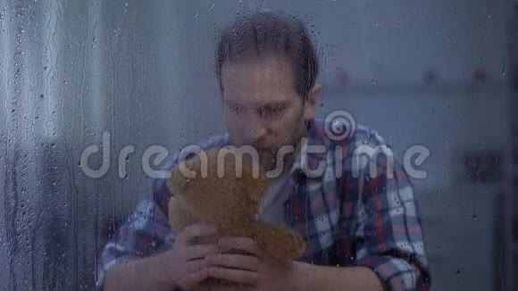 落单男子抱着泰迪熊在雨窗后离婚后失踪的孩子视频的预览图