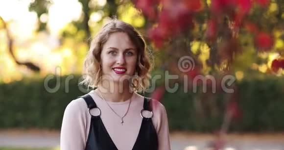 美丽的年轻女子中长的长发和红色的嘴唇在秋天公园视频的预览图
