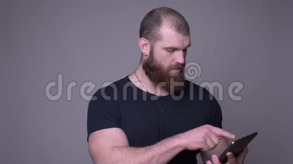 用平板电脑拍摄成年英俊肌肉发达留着胡须的白种人的特写镜头并用绿色屏幕拍摄视频的预览图