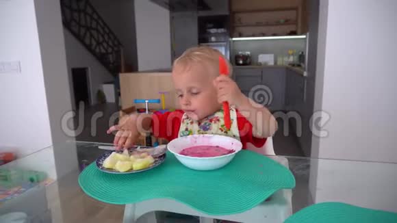 小男孩坐在桌子旁的高椅子上吃甜菜根汤万向节运动视频的预览图
