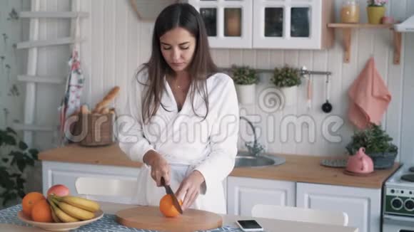 穿着白色浴袍的可爱女孩在厨房里穿着橙色衣服视频的预览图