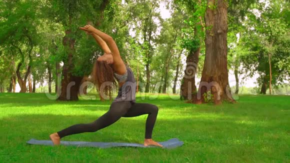 斯利姆女人在公园做阿萨纳勇士的姿势视频的预览图