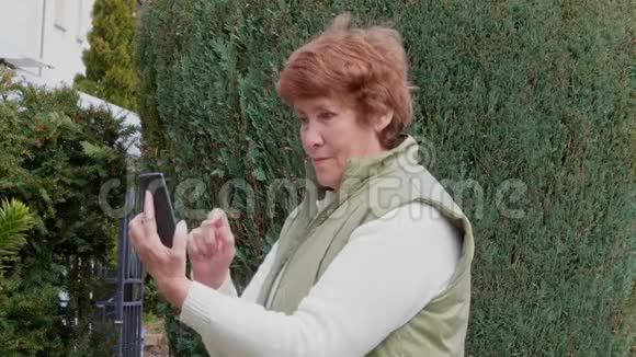 老年妇女拍照用手机在户外聊天视频的预览图