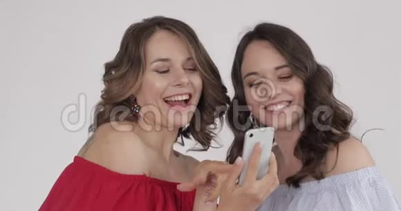 两个漂亮的女人看电话选择最好的自拍视频的预览图