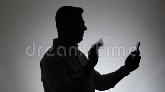 白色背景上的人的剪影一个男人在电话里说话的肖像脸上拿着一个小玩意视频的预览图
