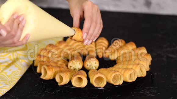 女人的手用管子把奶油注入角卷的两端用奶油做泡芙卷的女人视频的预览图