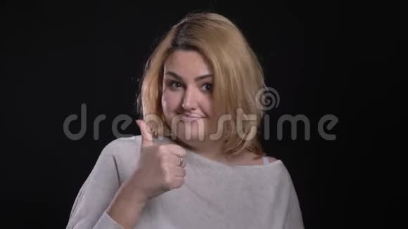 金发短发超重的女商人用手指示意在黑色背景上显示出喜欢和尊重视频的预览图