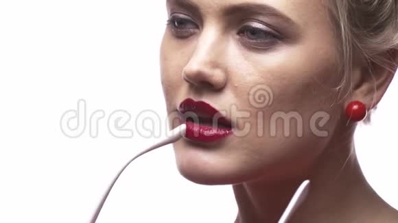一个涂着红色口红的漂亮金发女孩正咬着她的墨镜尖视频的预览图