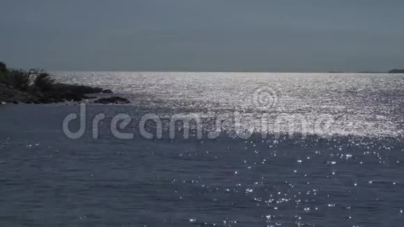 阳光在海面反射中间有黑褐色的岩石视频的预览图