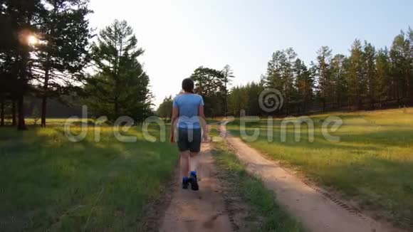 日落时走在乡村道路上的女孩背面视频的预览图
