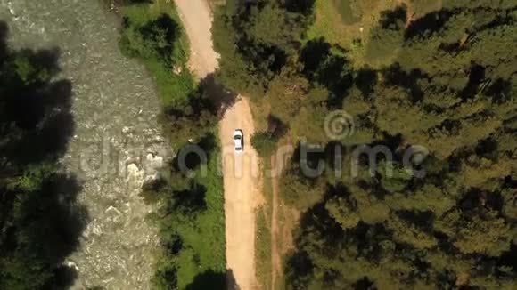 白色轿车沿着湍急的河流在路上行驶高空俯视图视频的预览图