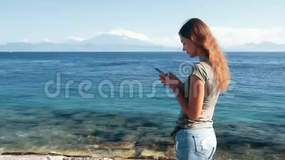 女旅行者使用电话在背景上输入信息海洋和山脉视频的预览图