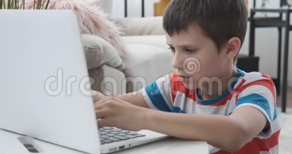 男孩在家里用笔记本电脑打字视频的预览图