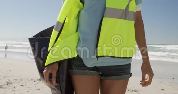 志愿者提着垃圾袋在沙滩上行走4k视频的预览图