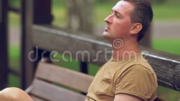 在户外长凳上抽烟的男人视频的预览图