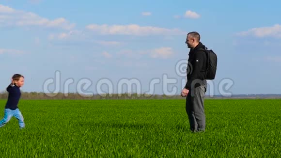 一个快乐的孩子穿过绿草跑到父亲的怀里父亲把孩子抱在怀里拥抱他视频的预览图