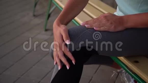 穿着黑灰色紧身裤的运动型女士用手搓揉擦伤的膝盖视频的预览图