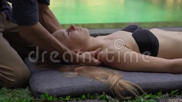 一位男性心理医生在一家私人别墅的游泳池旁为一位年轻女子做按摩的特写镜头家庭按摩视频的预览图