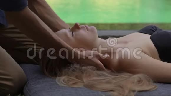 一位男性心理医生在一家私人别墅的游泳池旁为一位年轻女子做按摩的特写镜头家庭按摩视频的预览图