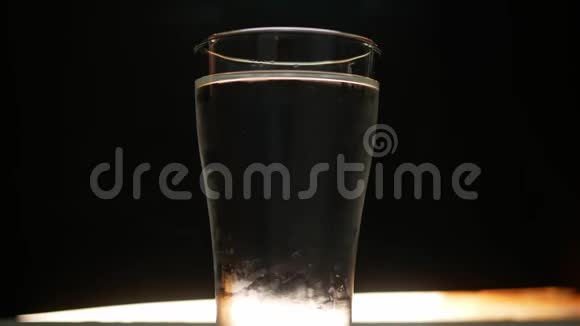 特写将冰块扔进装有水的玻璃杯在黑色背景上隔离视频的预览图