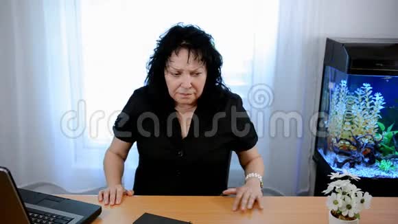 一个成熟的女人坐在办公室里有点惊慌失措视频的预览图